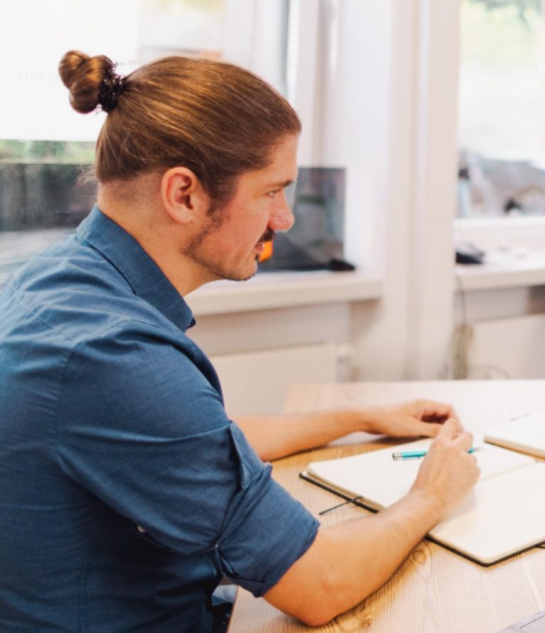Jonas Jagdziewski sitzt an einem Tisch und schreibt.