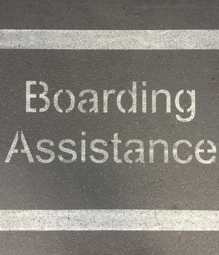 "Boarding-Assistance" in klaren, weißen Buchstaben auf schwarzem Asphalt.